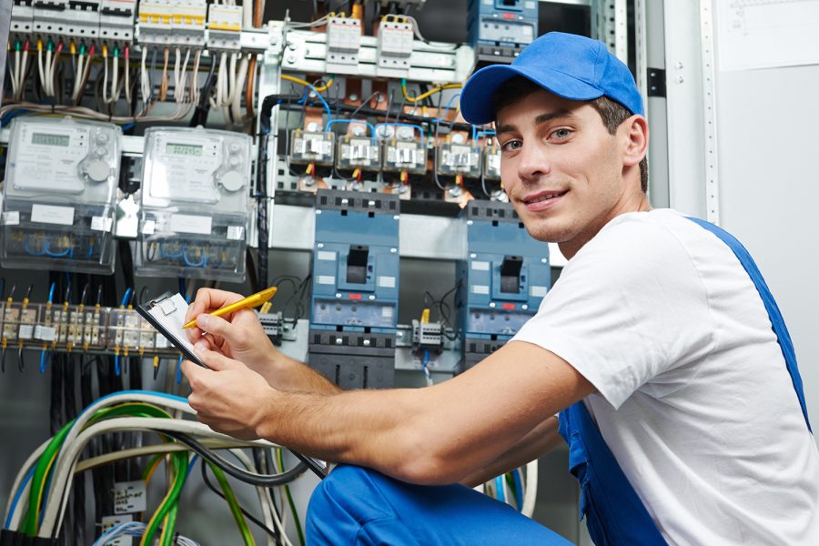 Young adult electrician builder engineer inspecting electric meter and equipment in distribution fuse box