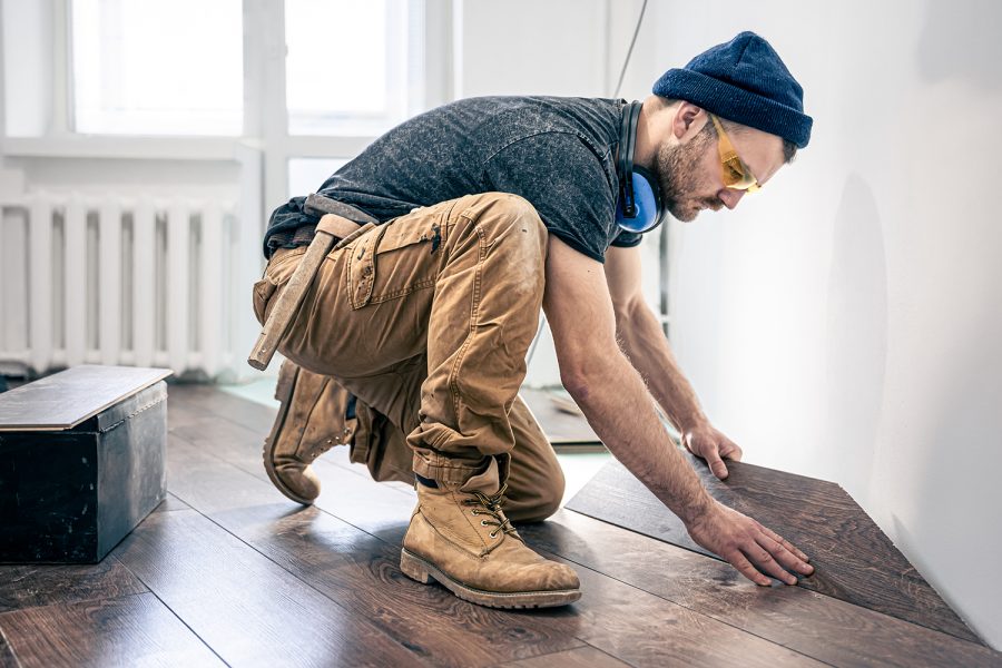 Carpenter on work putting wood parquet pieces. Home construction.