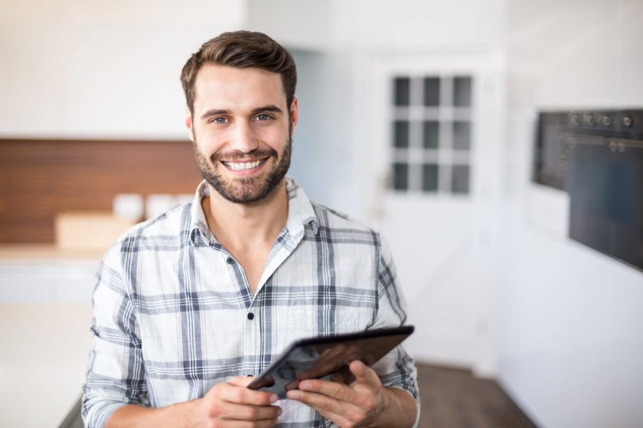 Close-up portrait of happy man using digital tablet in kitchen